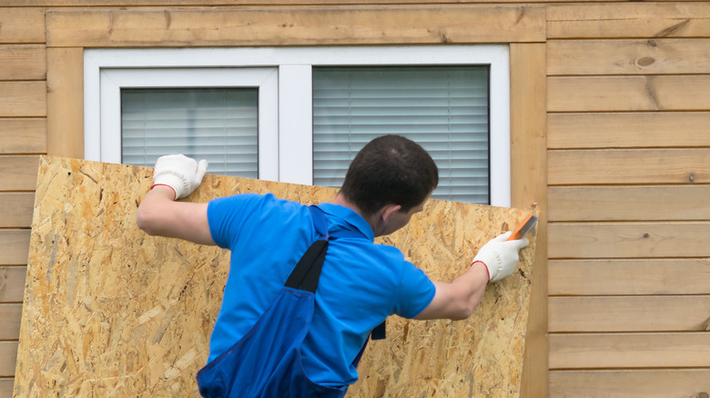 Person installing plywood over window