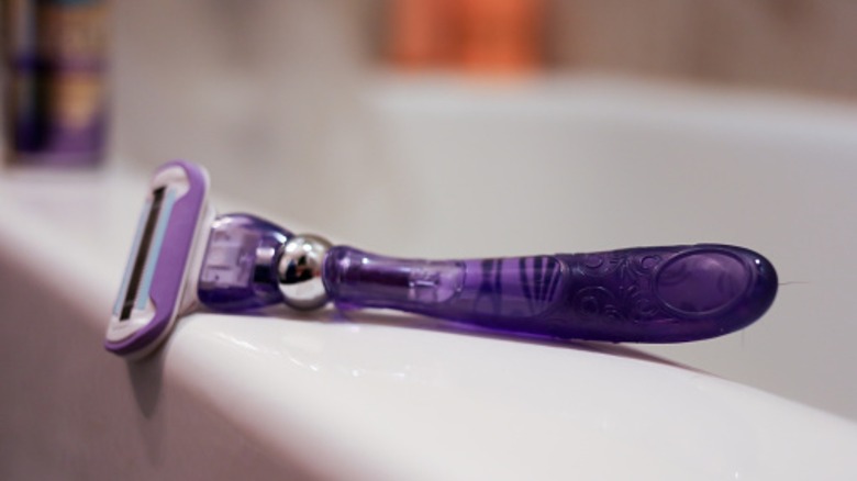 purple razor sitting on bathtub