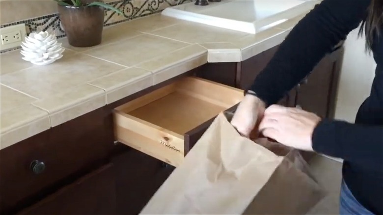 person opening bag near drawer