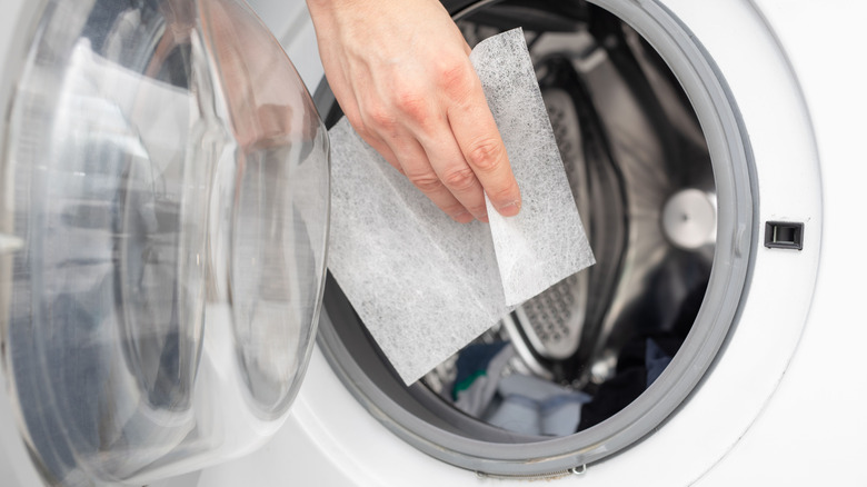 hand holding dryer sheet against dryer