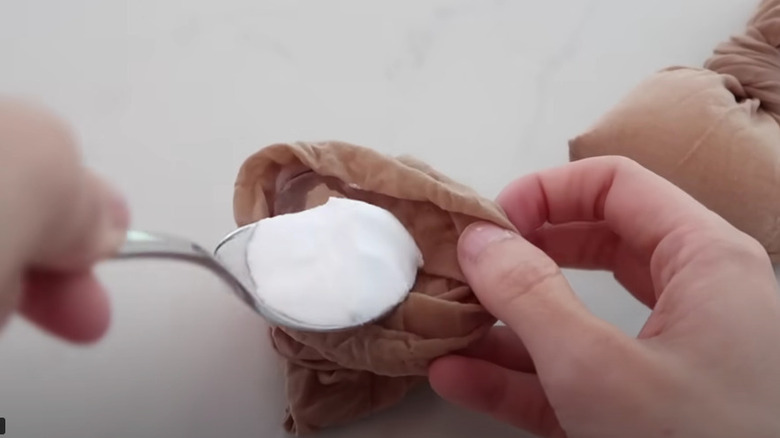 baking soda being poured into pantyhose