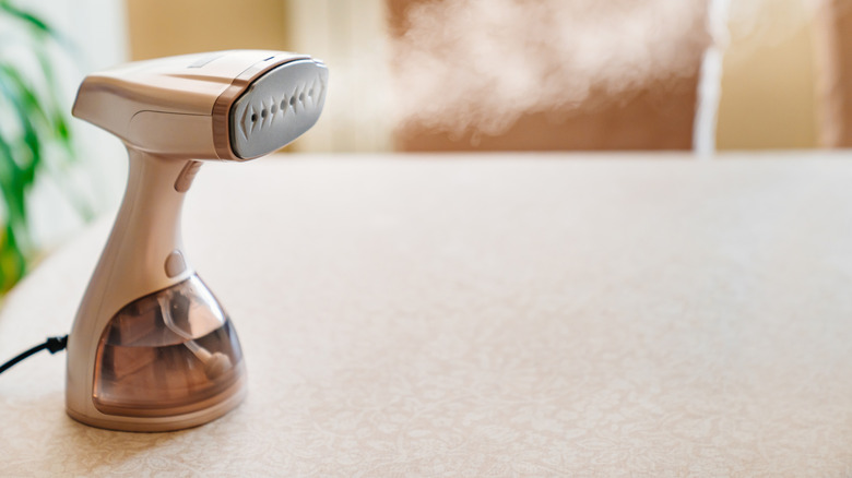 handheld cloth steamer with steam coming out of it