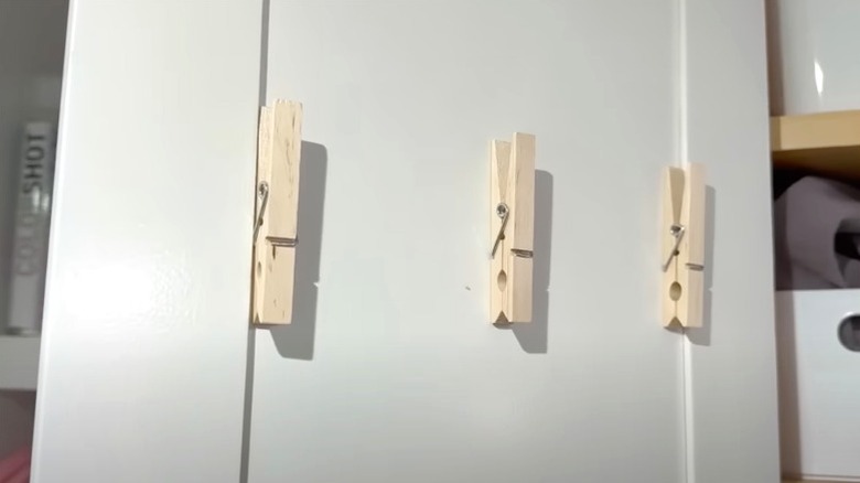 Three clothespins hanging in a line on back of cabinet door