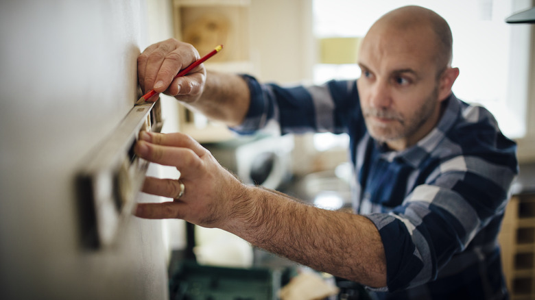 man marking wall with level