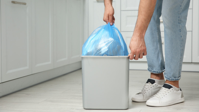 person taking trash bag out of trash can