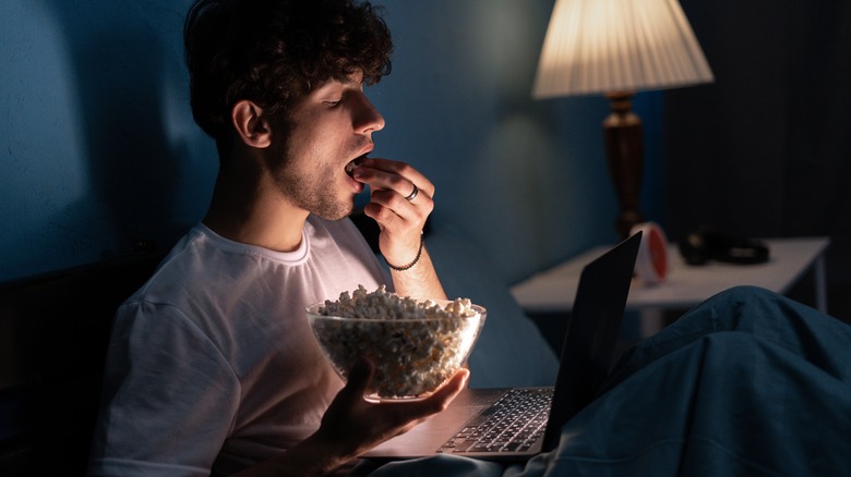 Person eating popcorn in bed