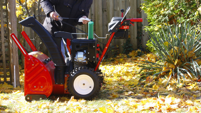 A person checking their snow blower's oil levels