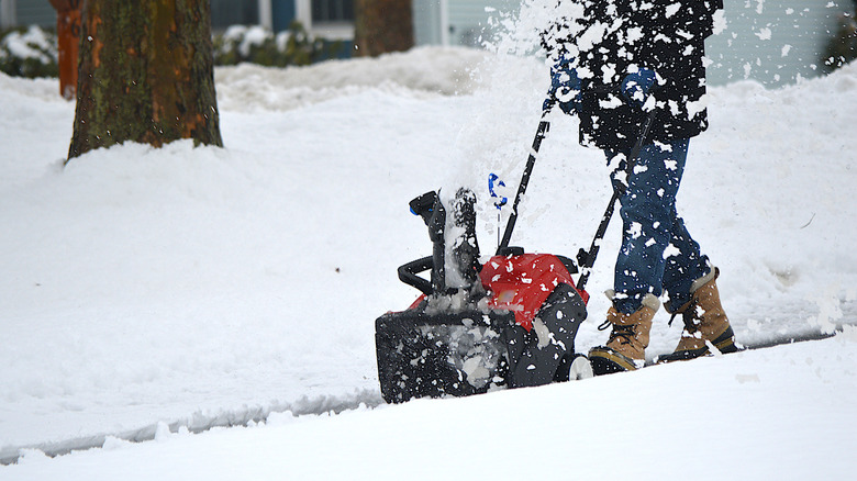 A person snow blowing a sidewalk