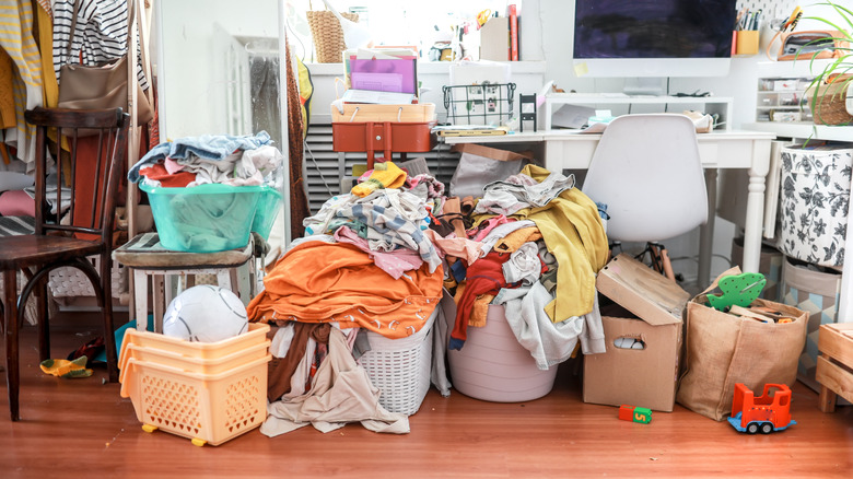 A cluttered room with several bins of disheveled items