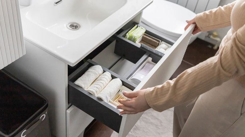 A person organizing a bathroom drawer