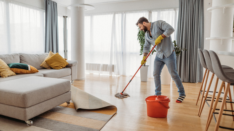 Man mopping living room floor