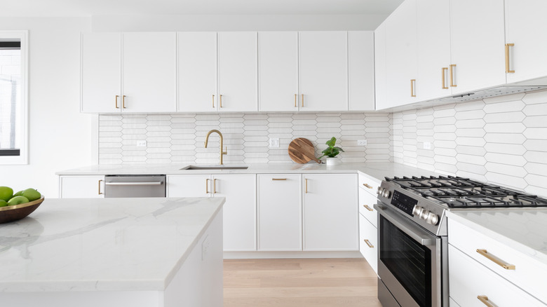 An all-white kitchen with an open upper cabinet.