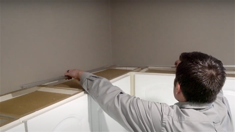 man installing lights above cabinets