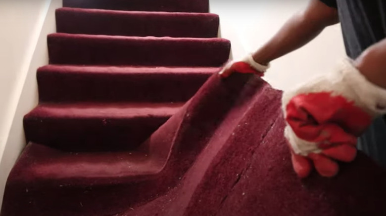 person removing red carpet stairs