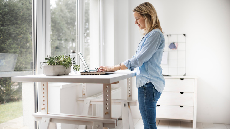 Person standing, working from table