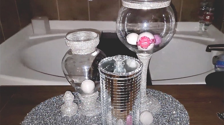 Apothecary jars with bling placed next to a bathtub