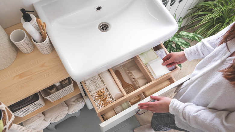 Woman looking at organized drawers under bathroom sink