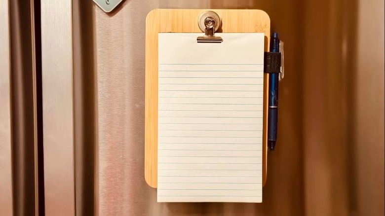 A DIY bamboo magnetic notepad holder is pictured on a stainless steel refrigerator door.