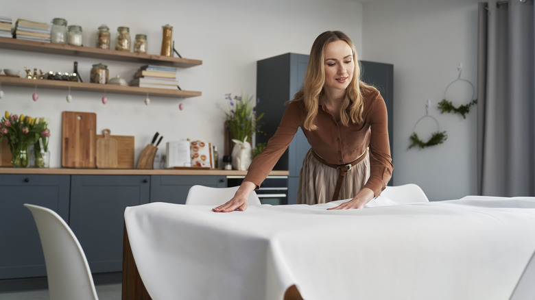 woman laying out white tablecloth