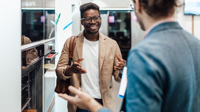 man talking to store associate about oven