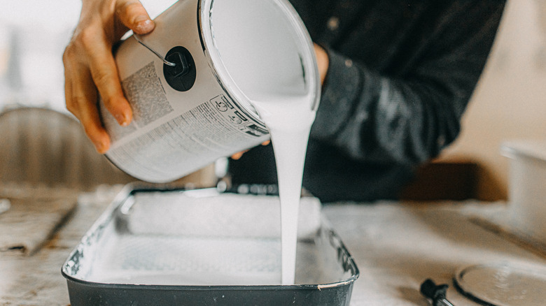 Person pouring paint into a paint tray