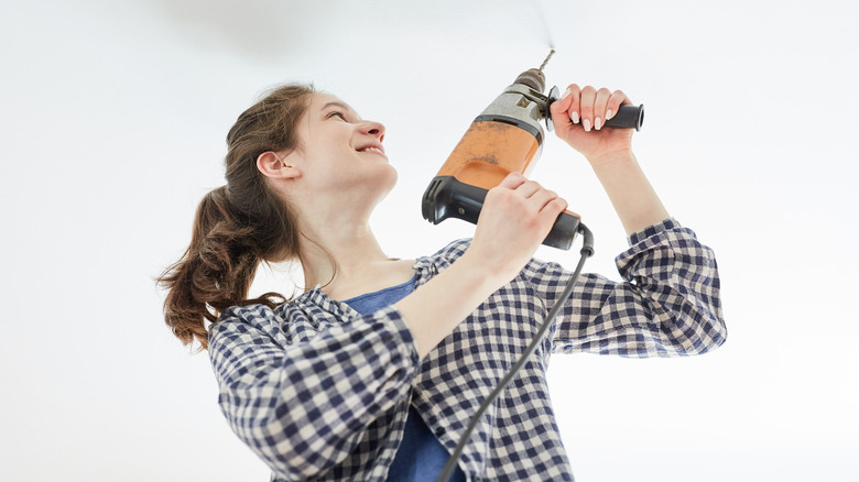 woman drilling into ceiling