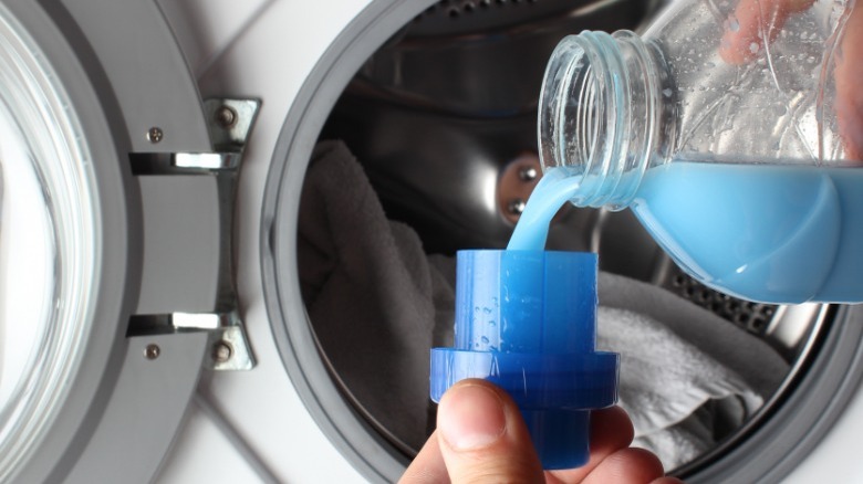 Pouring blue fabric softener into bottle lid