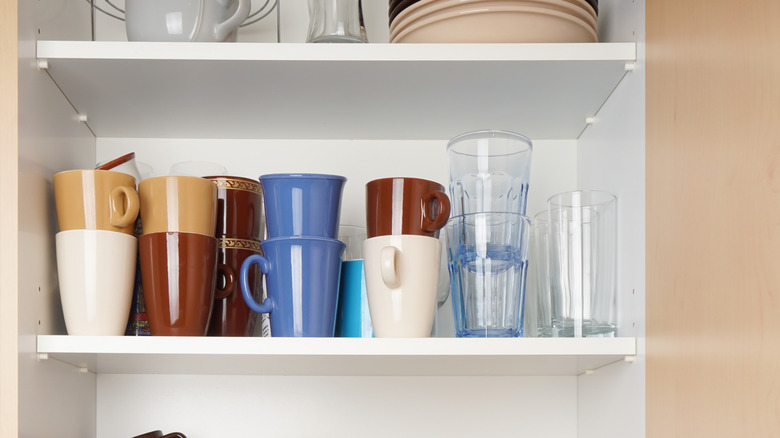 A cabinet holds a collection of mugs stacked on top of each other