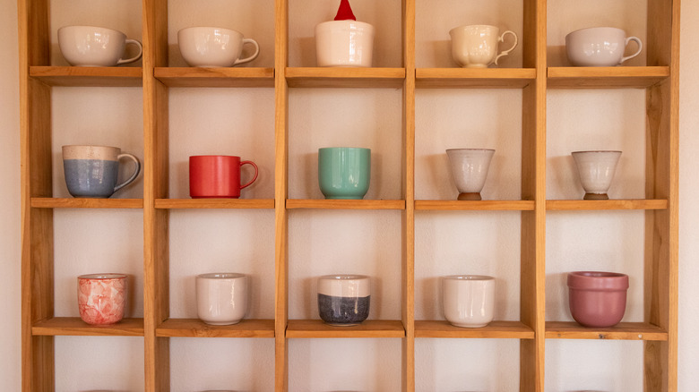 Rows of different styles of mugs line the wall in a display