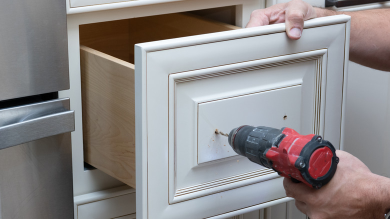 A person drills cabinet handles