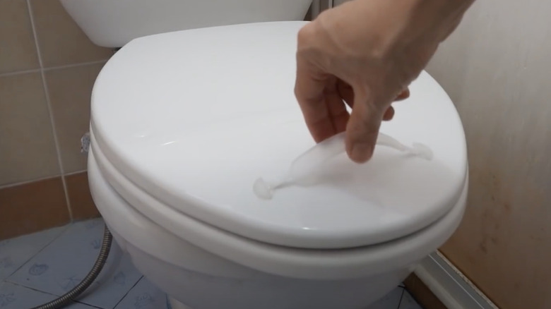 person attaching handle to toilet