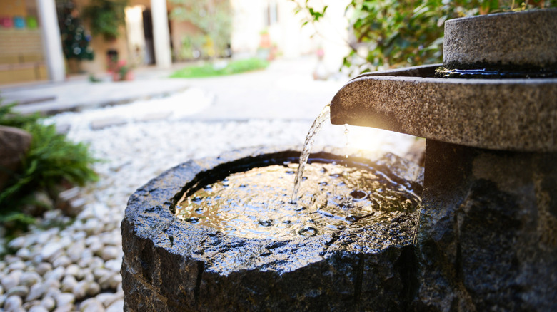 A tiered outdoor water feature made from stone sitting in a courtyard.