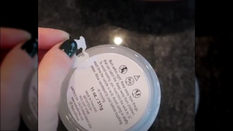 Person using a plastic bread tags to remove a sticker from a jar