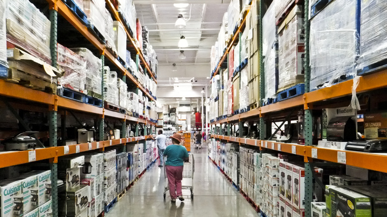 Person pushing a shopping cart down an aisle in Costco