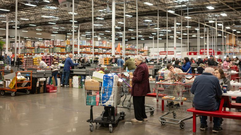 Inside of a Costco outlet with shoppers checking out and sitting down eating