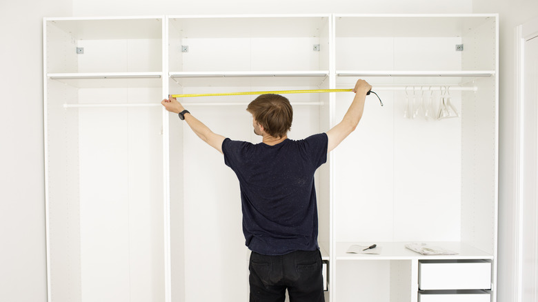 man measuring closet shelves