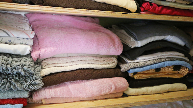 Blankets and bed linen on a storage shelf in a garage.