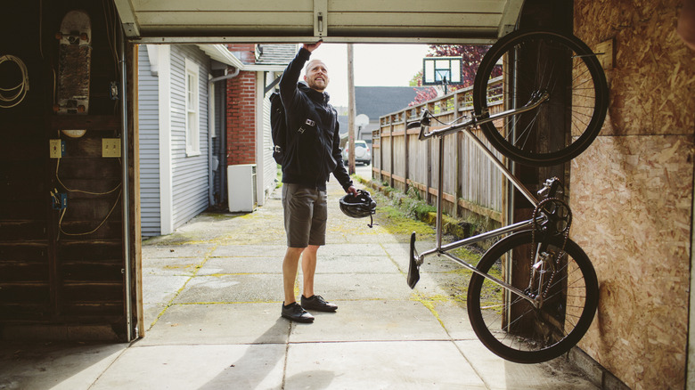 A man is closing his garage door after storing his bicycle in it