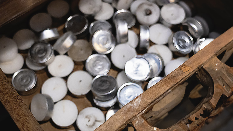 A jumble of tea light candles piled in a wooden drawer.