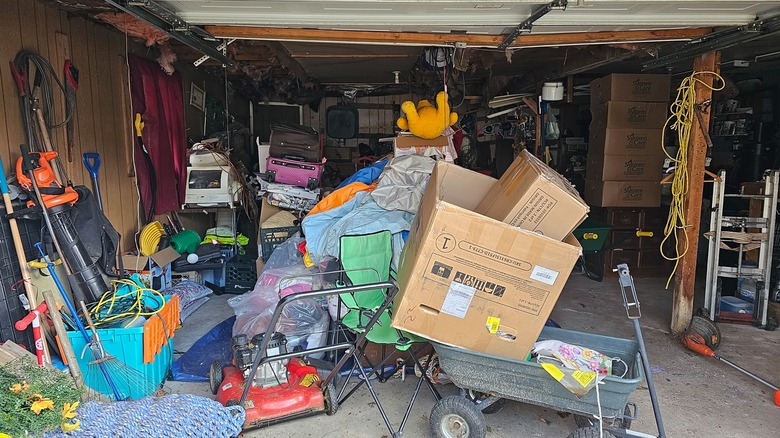 The inside of a garage is filled with household goods, yard items, and junk.