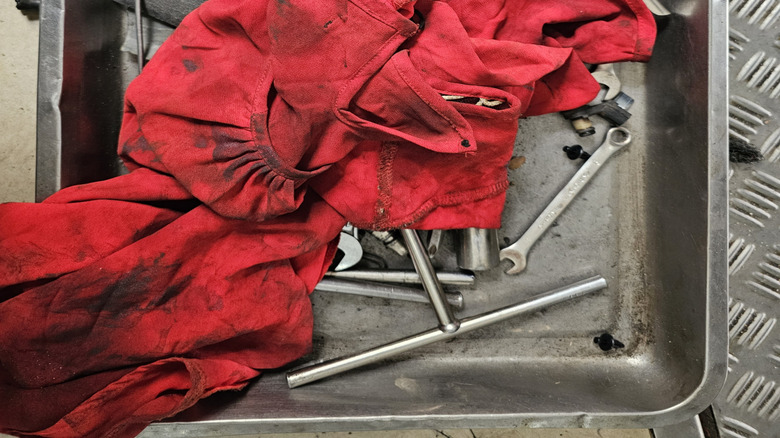 An oily red rag sits atop a metal tray full of tools.