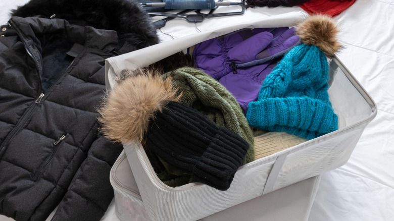 Winter clothing is being sorted and stored in large packing cubes.