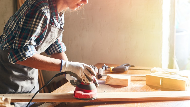 Woodworker sanding board in shop