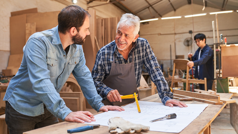 Carpenters discuss paper floor plan