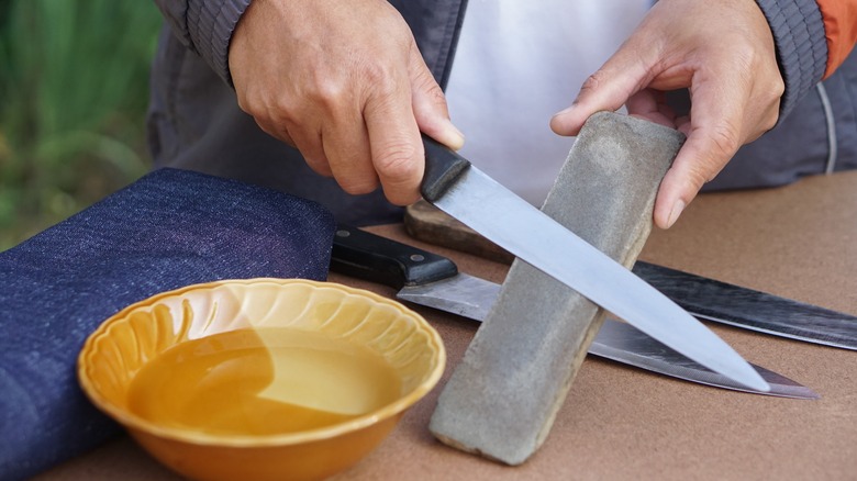 person sharpens knife on whetstone