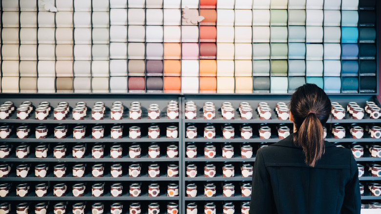 A woman looks at a wall of paint chips in a store