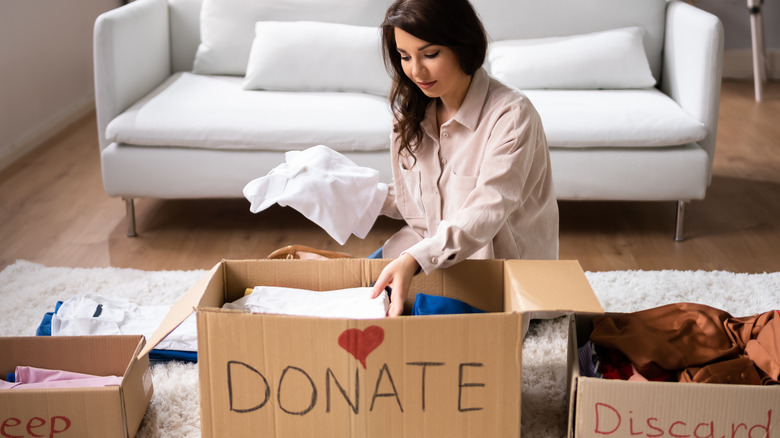 A woman organizes items into Keep, Donate, and Discard boxes