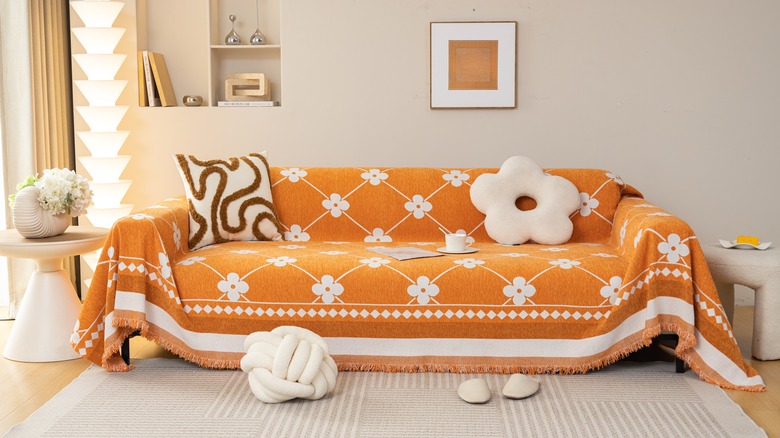 Sofa covered by orange slipcover with white flowers