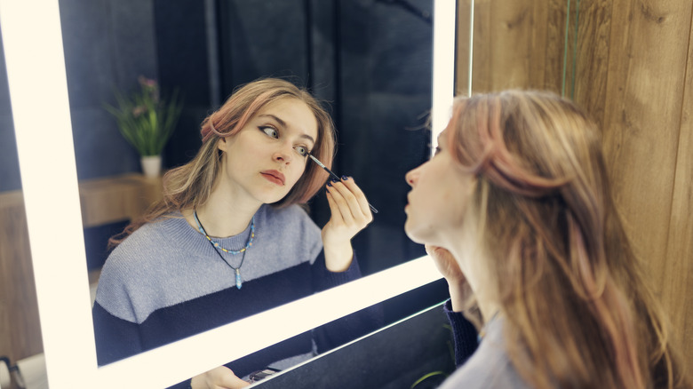 A woman does make up with LED lights in mirror