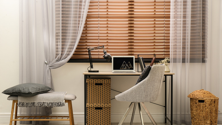 Brown blinds and sheer curtains on window